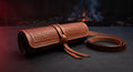 Hand tooled leather knife roll with a basket weave face, rolled up and tied shut with its leather strap