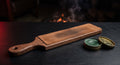 Leather strop board on a walnut paddle beside an open tin of green polishing compound