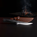 Hand forged boning knife with a 5 inch straight carbon steel blade, black micarta handle and a stamped leather sheath