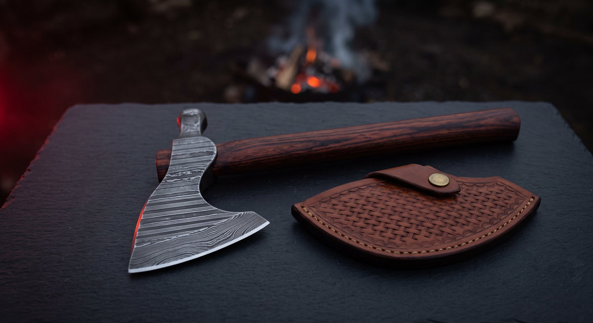 Damascus bushcraft axe with a ladder pattern head, rosewood handle and a stamped leather head cover