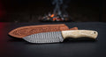 Damascus bushcraft knife with a ladder pattern blade, camel bone handle and a hand carved leather sheath