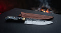 Hand forged chef knife with an 8 inch blade, black buffalo horn handle and a brass bolster