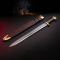 Damascus viking sword with brass guard and lobed pommel and a tooled leather scabbard