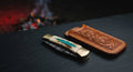 Closed Damascus folding knife with a camel bone handle, crushed turquoise inlay and brass bolsters