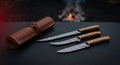 Damascus fillet and boning knife set of three with olive wood handles beside a closed tooled leather knife roll