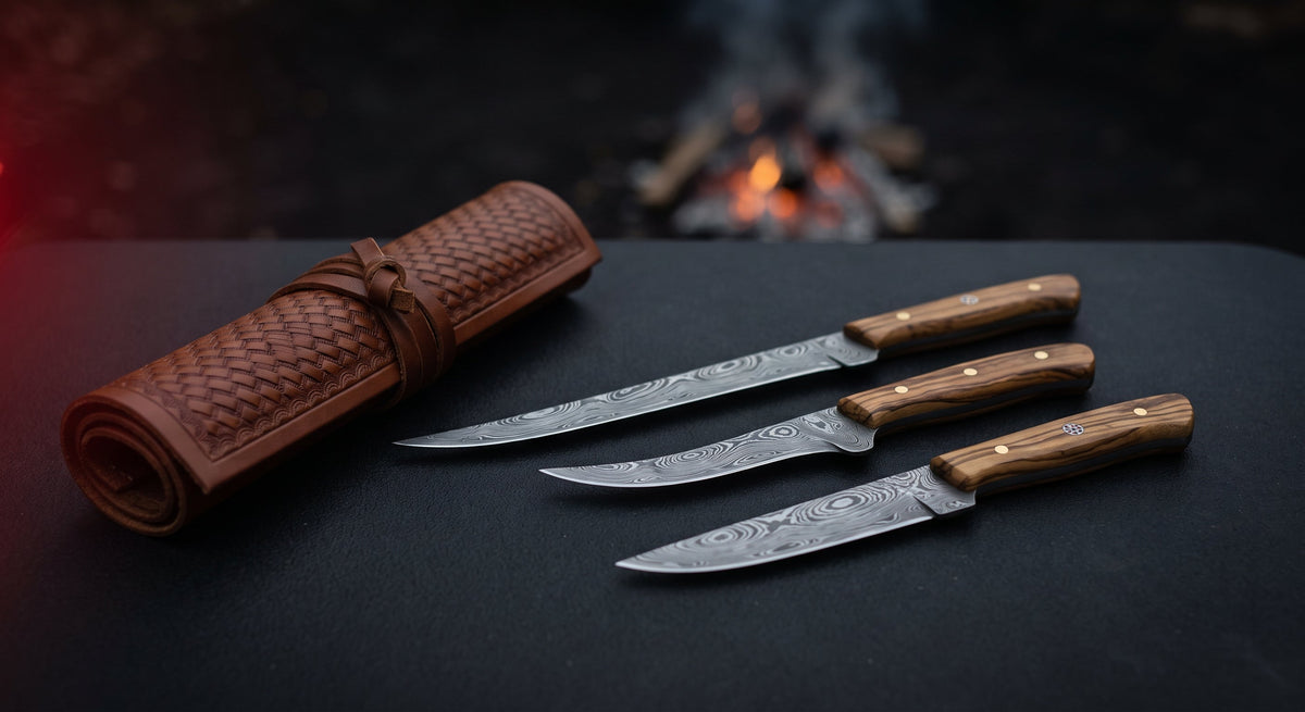 Damascus fillet and boning knife set of three with olive wood handles beside a closed tooled leather knife roll