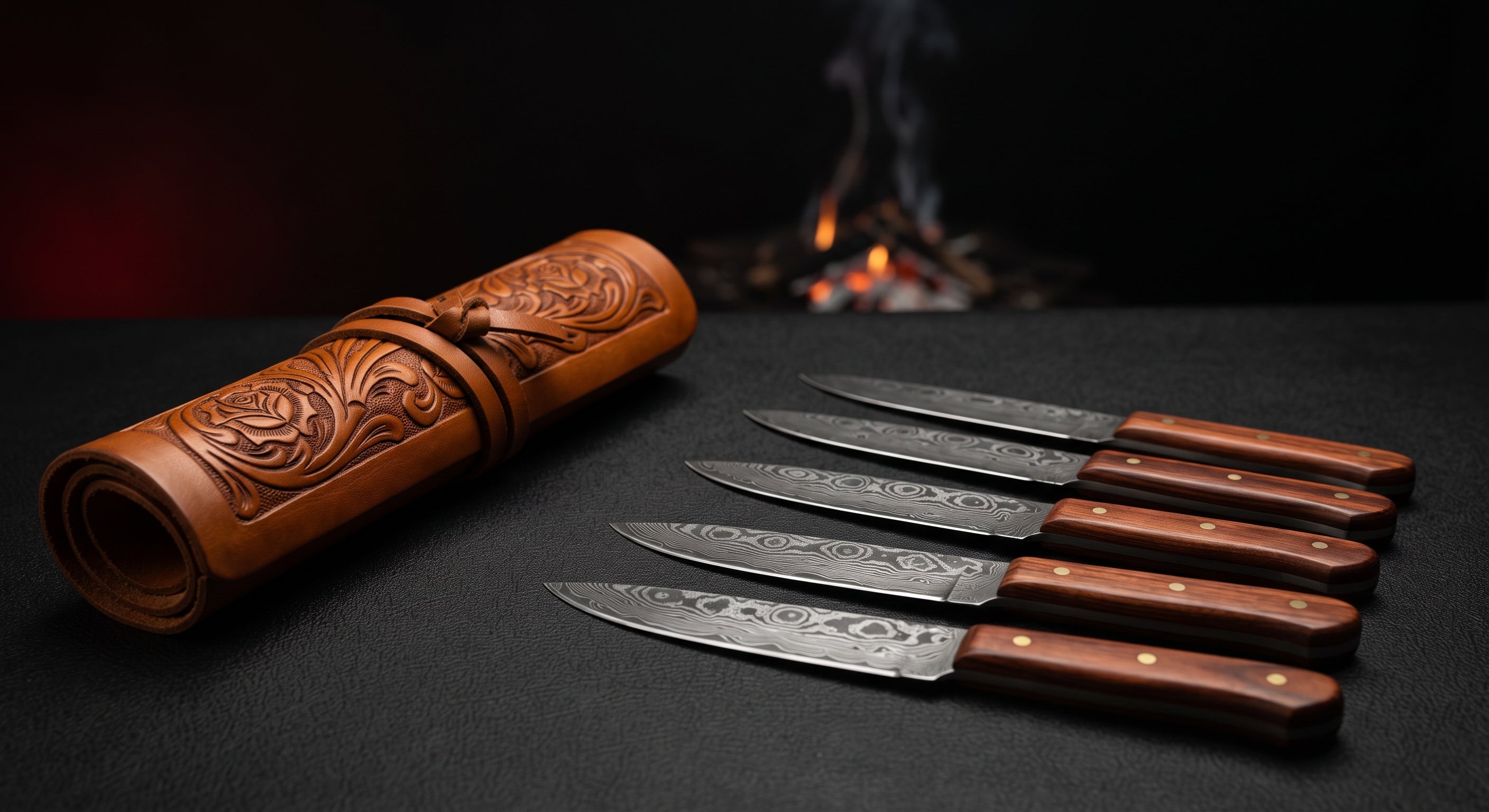 Damascus steak knife set of five with rosewood handles beside a closed hand carved leather knife roll
