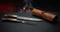 Damascus carving knife and fork with stag antler handles beside a closed hand carved leather roll