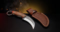 D2 steel karambit knife with brown micarta handle, finger ring and tooled leather sheath