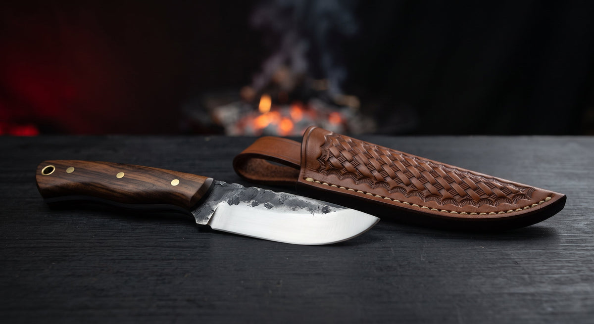 Hand forged skinning knife with a wide sweeping belly, dark forged spine and a walnut handle