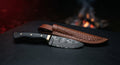 Damascus skinner knife with a ladder pattern blade, black ebony handle and a brass bolster