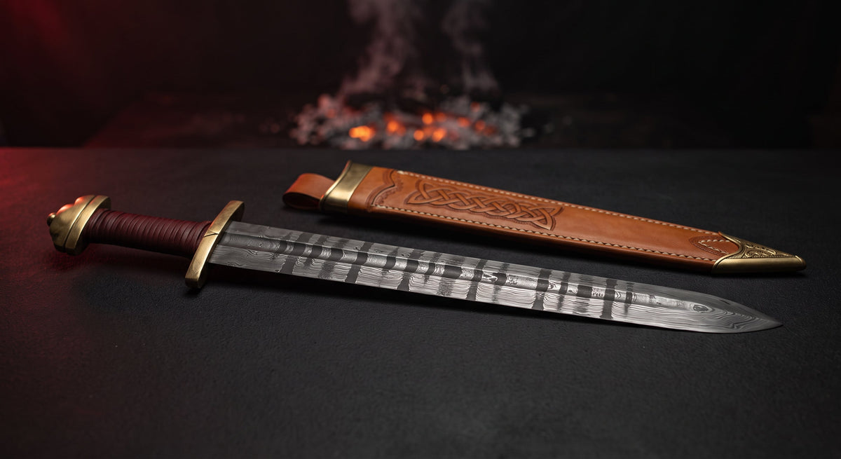 Damascus viking sword with a ladder pattern fullered blade, brass lobed pommel and a hand carved leather scabbard