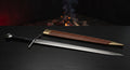 Hand forged medieval arming sword with a tapered fullered blade, flat iron wheel pommel and a stamped leather scabbard