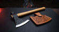 Hand forged tomahawk with brass tacks in a hickory handle and a hand carved leather head cover
