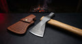 Damascus tomahawk with a raindrop pattern head, hickory handle and a stamped leather head cover